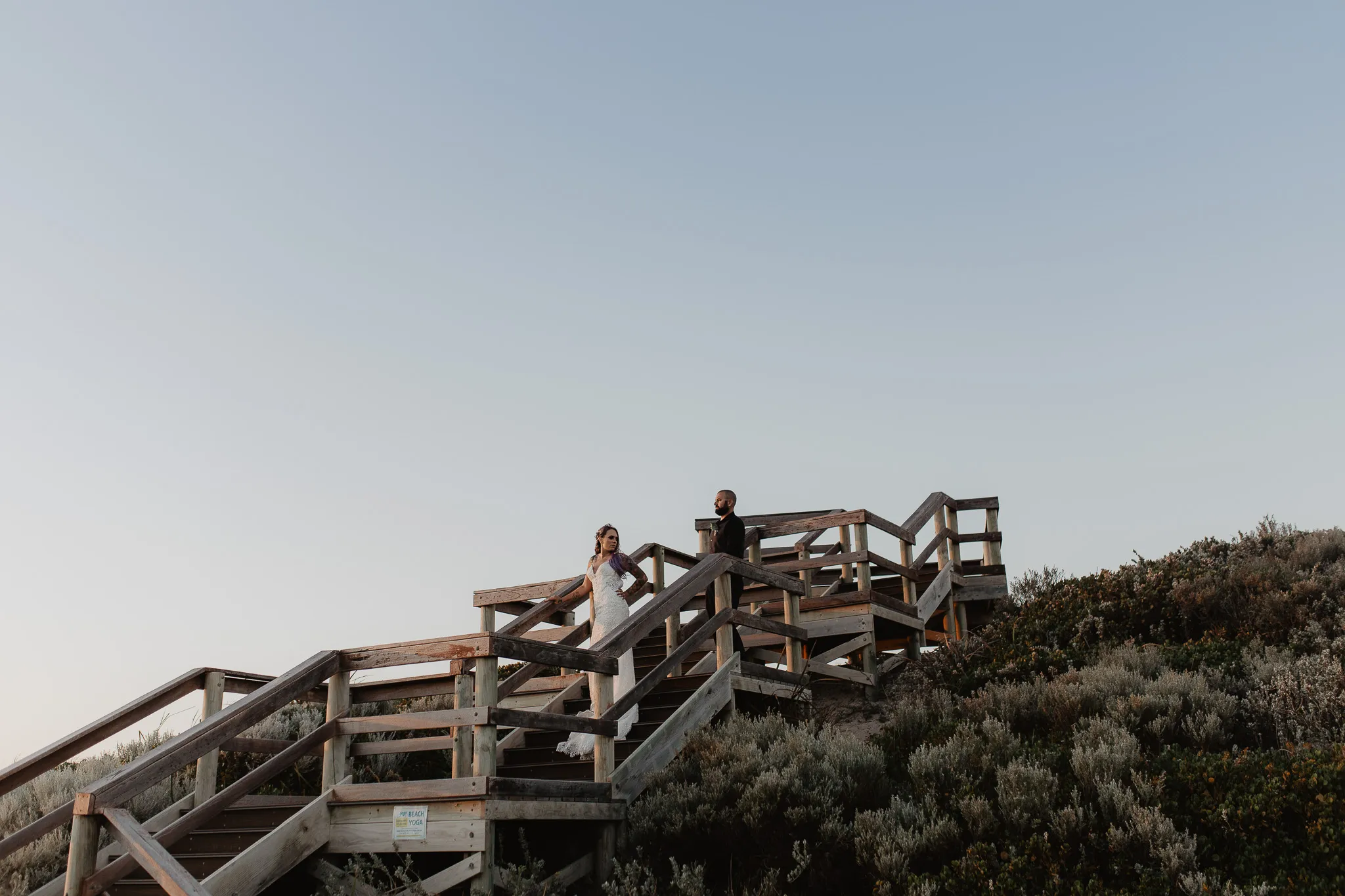 Elopement couple on a wooden beach staircase at sunset